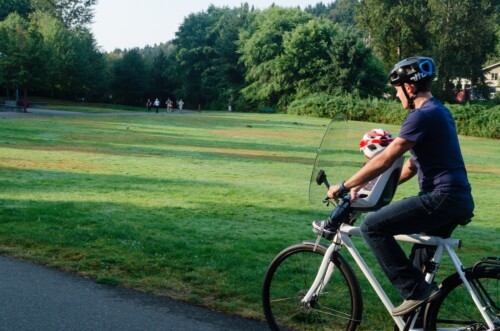 dad biking with baby in observer child seat and windscreen attachment